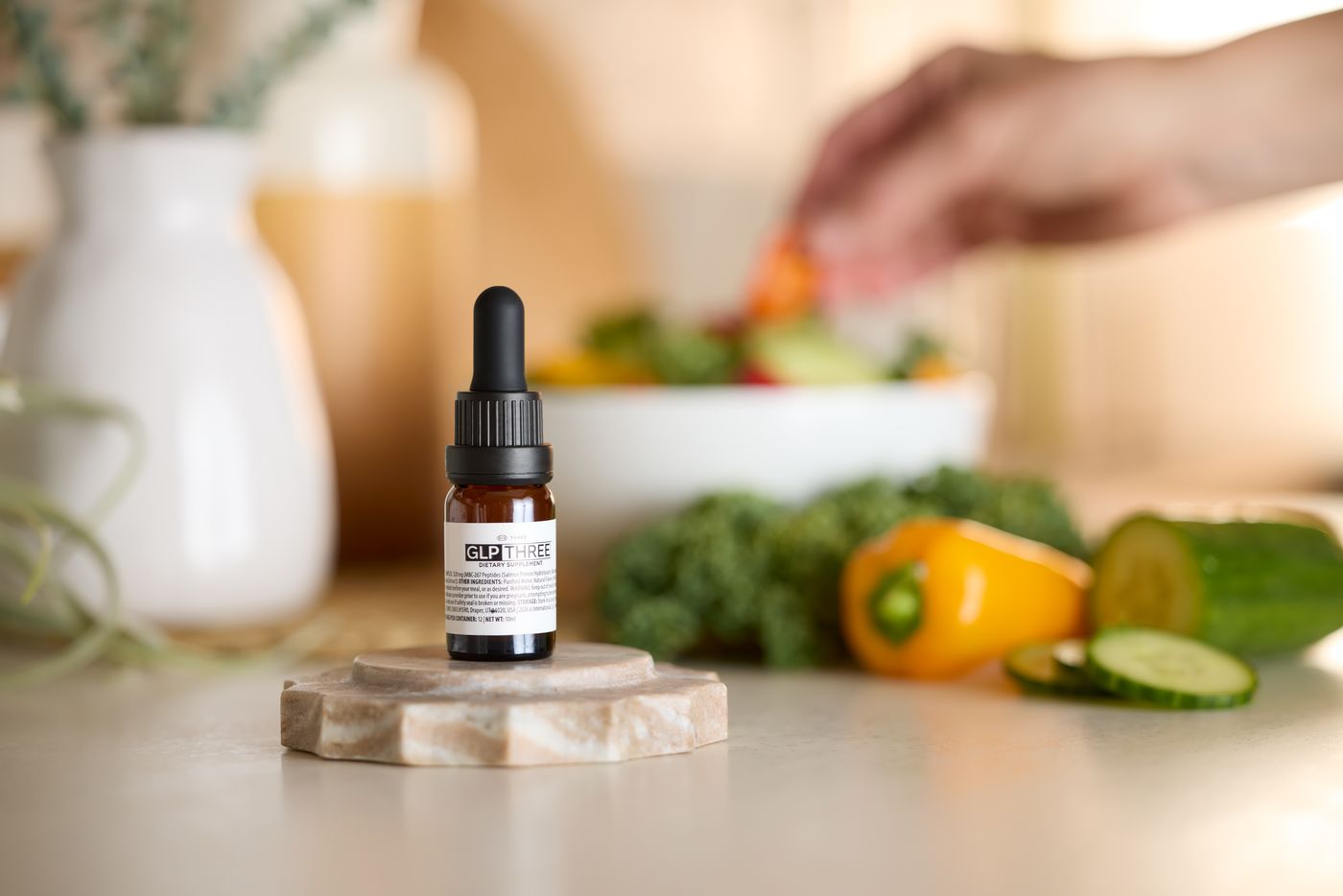 GLP-THREE bottle on a kitchen counter while a fresh salad is prepared